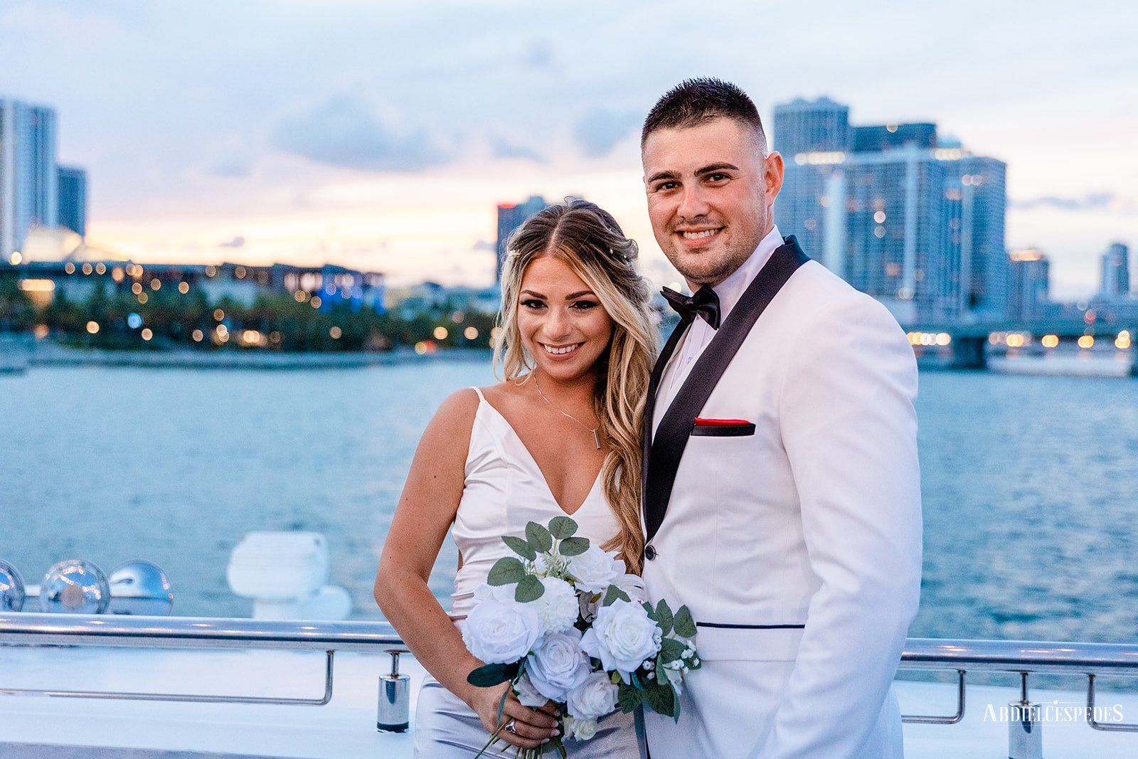 Newlywed couple on deck at golden hour with the Miami waterfront behind them